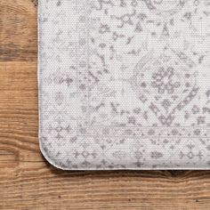 a close up of a white and gray pattern on a wooden surface with wood flooring