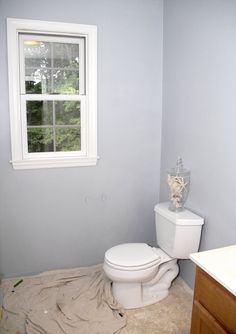 a white toilet sitting next to a window in a bathroom under renovation work on the floor