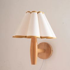 a wooden wall light with a white shade on the lamp is mounted to a wall