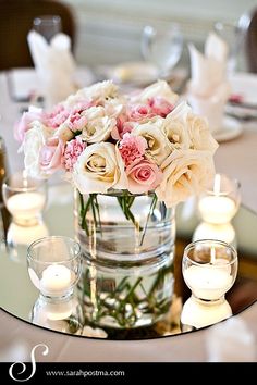 a vase filled with lots of white and pink flowers on top of a glass table