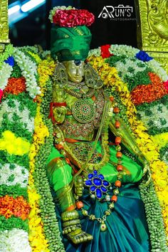 an idol is sitting in the middle of flowers and garlands on it's head