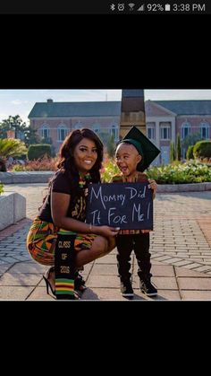 a woman holding a sign next to a little boy wearing a graduation cap and gown