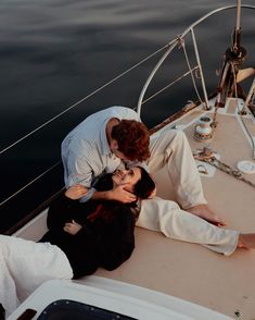 two people are sitting on the deck of a boat and one person is kissing the other