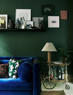 a living room with green walls and pictures on the shelf above it, along with a blue couch