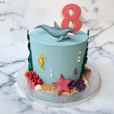 a birthday cake decorated with sea animals and seashells on a marble countertop