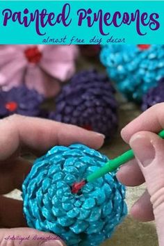 someone is painting pine cones with blue and pink colors on them, as if they were crocheted