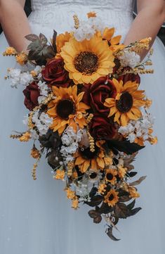 a bride holding a bouquet of sunflowers and roses