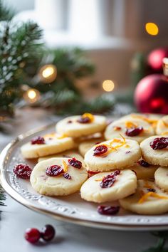 cookies with cranberry sauce and orange zest are on a plate next to christmas decorations