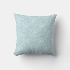 a light blue pillow with white flowers on the front and back, against a white wall