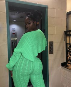 a woman standing in an elevator with her back to the camera and wearing green clothing