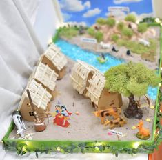 a cake decorated to look like a village with people and animals on the beach in front of it