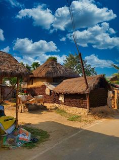 a small village with thatched roof houses and cows grazing in the grass next to it