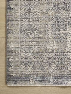 a gray and white rug on top of a wooden floor with a wood floor in the background