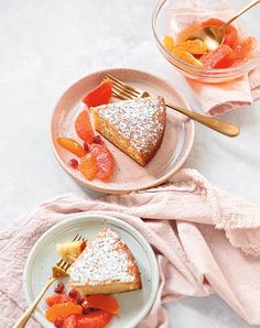 two plates with slices of cake and fruit on them next to a glass of orange juice