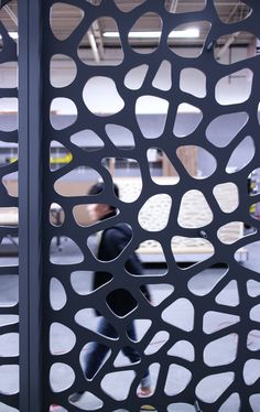 a skateboarder is seen through the holes in a metal fence that has been designed to look like an abstract pattern