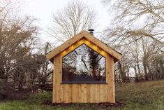 a small wooden building with windows and lights on the roof, in front of some trees