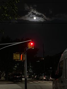 a van is stopped at an intersection with the moon in the background