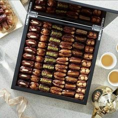 a tray filled with lots of different kinds of food next to cups and saucers