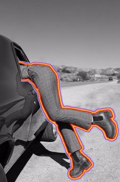 a man laying on the back of a car with an orange neon strip around his body