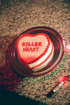 a red and white heart shaped cake with the words killer heart written on it sitting on a counter