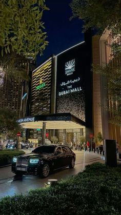 a black car parked in front of a tall building with lights on it's side