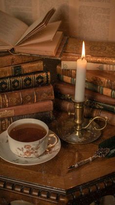 a cup of tea next to some books and a candle