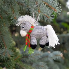 a knitted horse ornament hanging from a pine tree