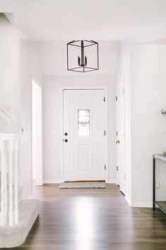 an empty hallway with white walls and wood flooring is seen in this image from the front door