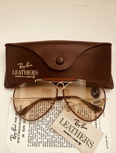 Please read all the description and check all photos before buying . you are buying a new old stock  vintage aviator outdoorsman shooter leather  ray ban sunglasses bausch & lomb  b&l usa  in new condition  size 62mm  [ large size ]   lenses are brown changeable photochromic self changing   in new mint condition without any scratches . on the top of bridge reads " bl ray ban usa " frame is gold and  brown perforated leather ,, limited edition leather ,, very pretty  ray ban logo on the right len Retro Brown Aviator Sunglasses, Cheap Vintage Aviator Sunglasses, Cheap Retro Brown Aviator Sunglasses, Luxury Vintage Aviator Sunglasses For Summer, Luxury Casual Brown Aviator Sunglasses, Luxury Vintage Men's Sunglasses, Luxury Vintage Aviator Sunglasses With Tinted Lenses, Luxury Brown Aviator Sunglasses, Vintage Brown Aviator Sunglasses