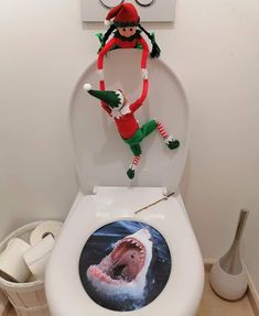 an elf on the back of a toilet with a shark in it's mouth