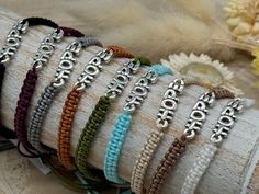 a bunch of bracelets that are sitting on a piece of cloth with flowers in the background