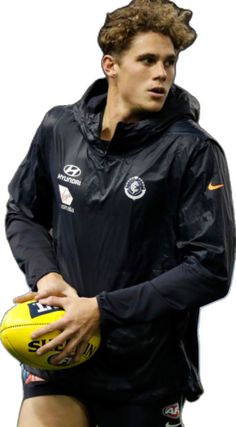 a young man holding a yellow football in his right hand and wearing a black jacket