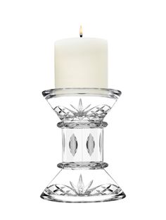 a glass candle holder with a lit candle in it's center and an intricate design on the bottom