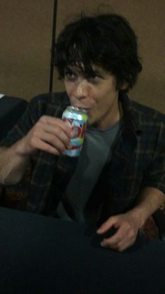 a man sitting on a couch drinking from a can