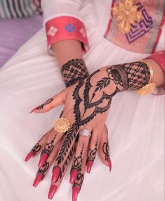 a woman's hands with hennap and rings on them, sitting in a white dress