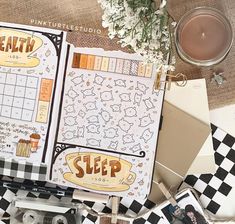 an open planner book sitting on top of a checkered table cloth next to a cup of coffee