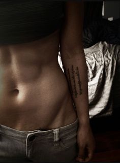 a woman's stomach with a tattoo on her left side and words written in the lower half