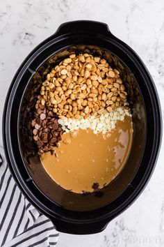 the ingredients to make peanut butter and chocolate pudding in a crock pot on a marble counter top