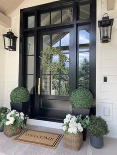 two potted plants are sitting on the front step of a house with a welcome mat