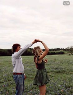 two people standing in a field with one holding the other's hand up to their head