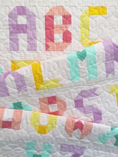 a quilted wall hanging with letters on it