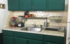 a kitchen with green cabinets and a silver sink