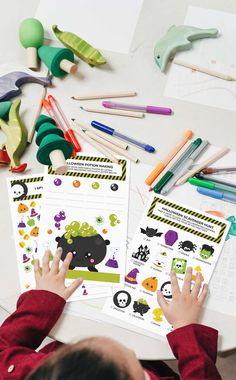 a young boy sitting at a table with lots of paper and crayons on it