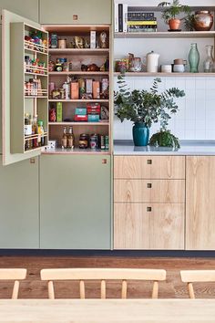 a kitchen with wooden cabinets and shelves filled with food on top of each shelf, next to a dining room table