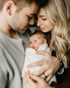 a man and woman holding a baby in their arms