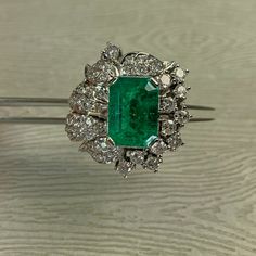 This Platinum Vintage Ring has a stunning large emerald as its center piece. The emerald has strong intense green color and shimmers as you move the piece around! The emerald is set with prongs and on all sides surrounded with sparkly high quality eye clean diamonds in flower petal shapes. There are a total of 57 round brilliants for a total of 2 carats. The ring is a size 7.5. This ring is a great collector's piece with its sparkly flowery design and good quality large emerald! Ring Size: 7.5 T Luxury Green Diamond Ring In Platinum, Green Oval Emerald Ring In Platinum, Luxury Green Diamond Ring With Vvs Clarity, Luxury Cluster Emerald Ring With Diamonds, Luxury Platinum Cluster Emerald Ring, Elegant Platinum Emerald Cluster Ring, Green Platinum Emerald Ring With Cluster Shape, Platinum Cluster Emerald Ring, Green Emerald Cluster Ring In Platinum