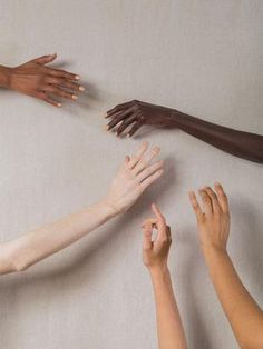 several hands reaching up towards each other on a white surface with one hand in the air