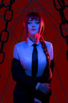 a woman with red hair wearing a black tie and white shirt is standing in front of chains