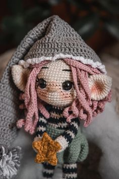 a crocheted doll with pink hair wearing a hat