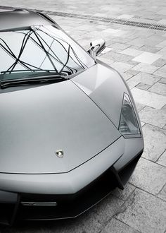 a silver sports car parked on top of a sidewalk